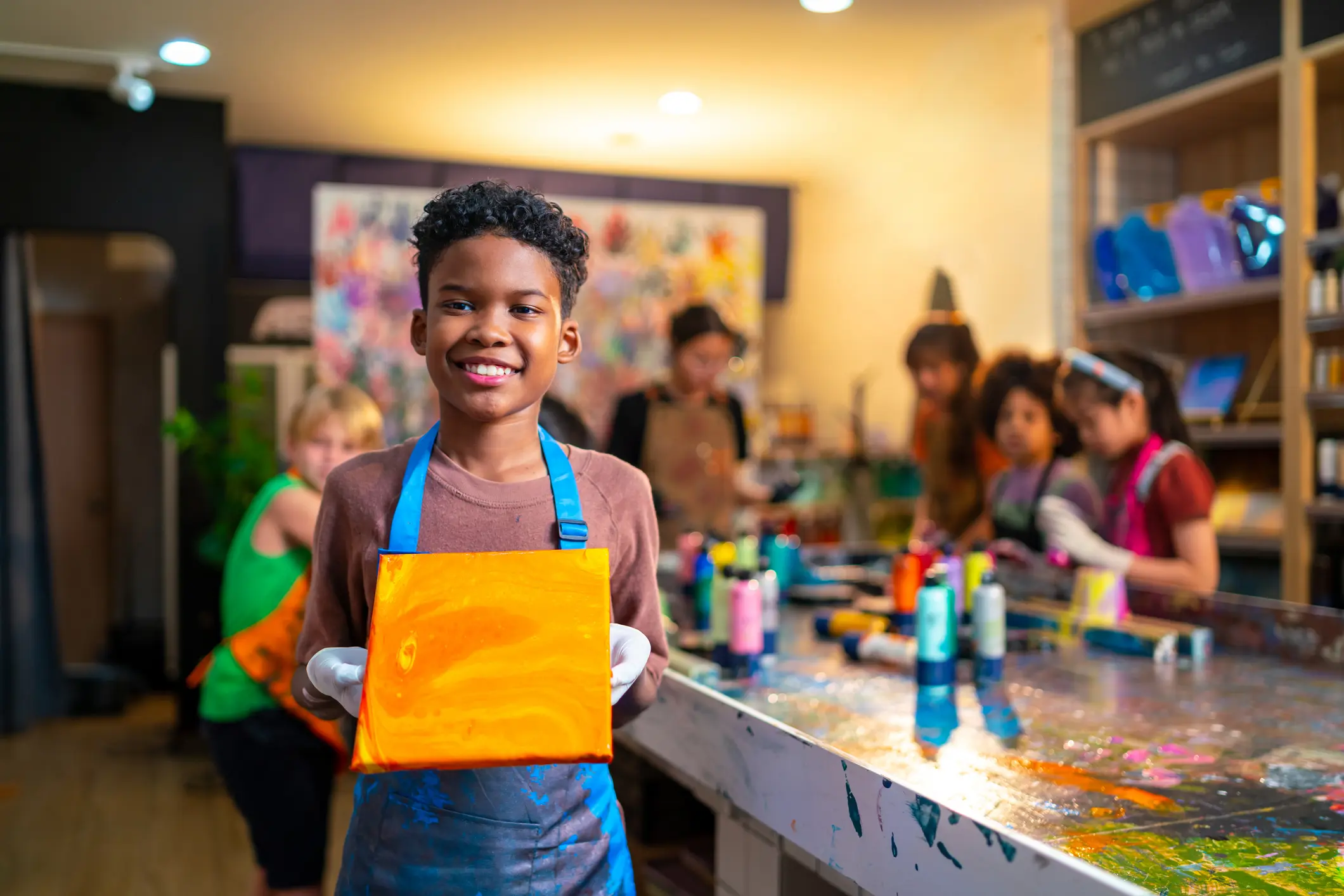 Child holding orange painting in art class.