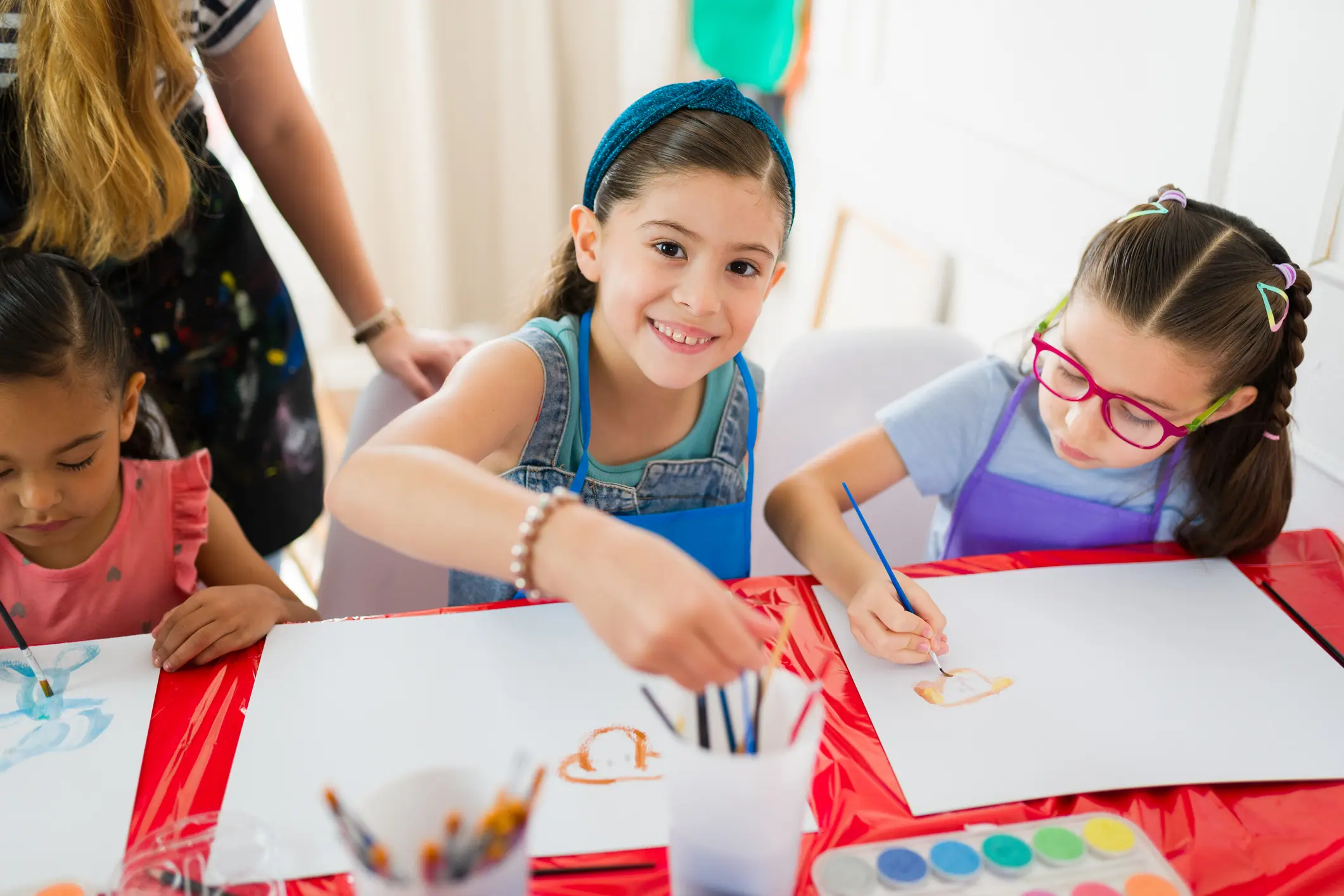 Children painting at a red table