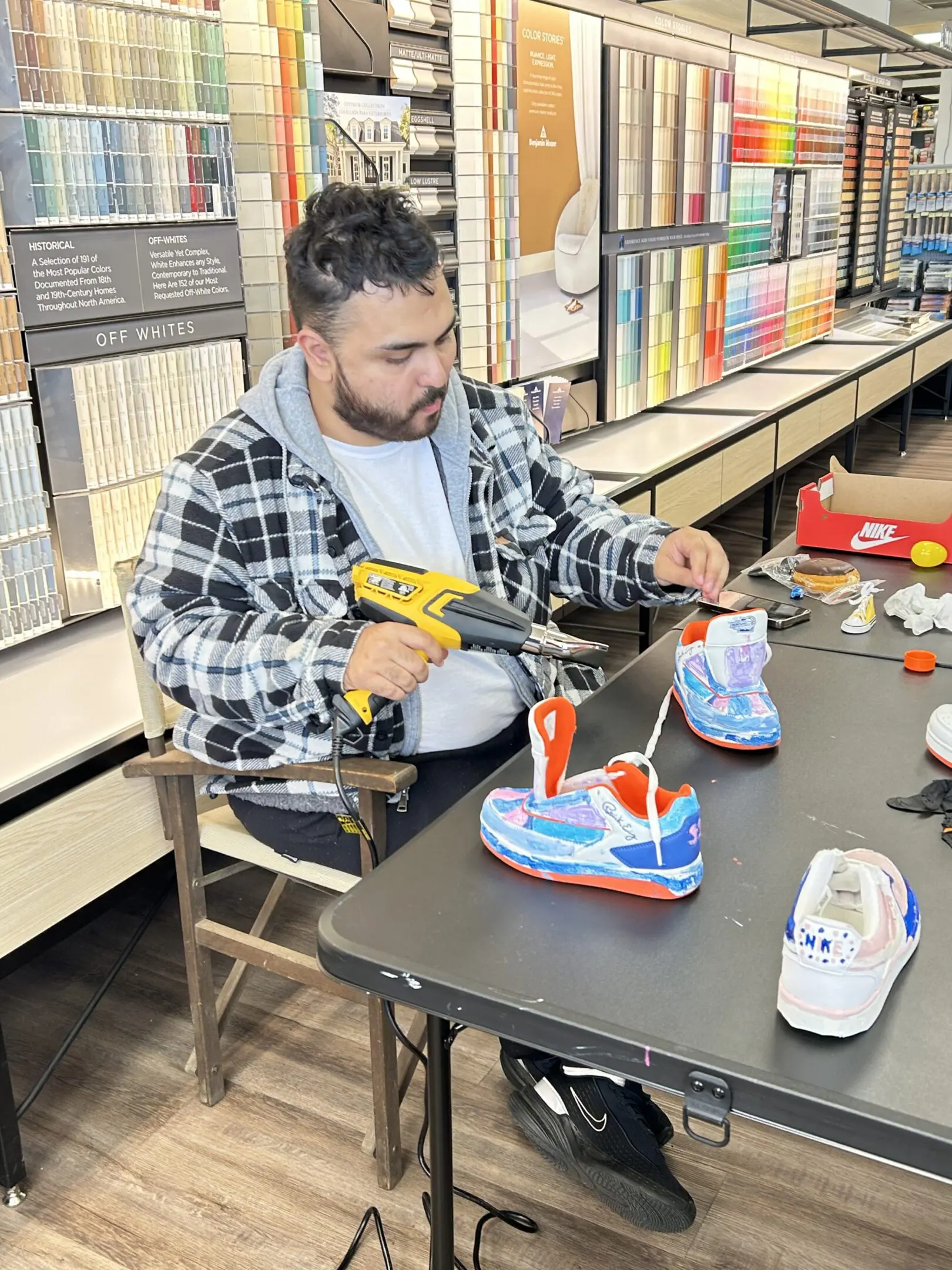 Man customizing sneakers with a power drill at a table.