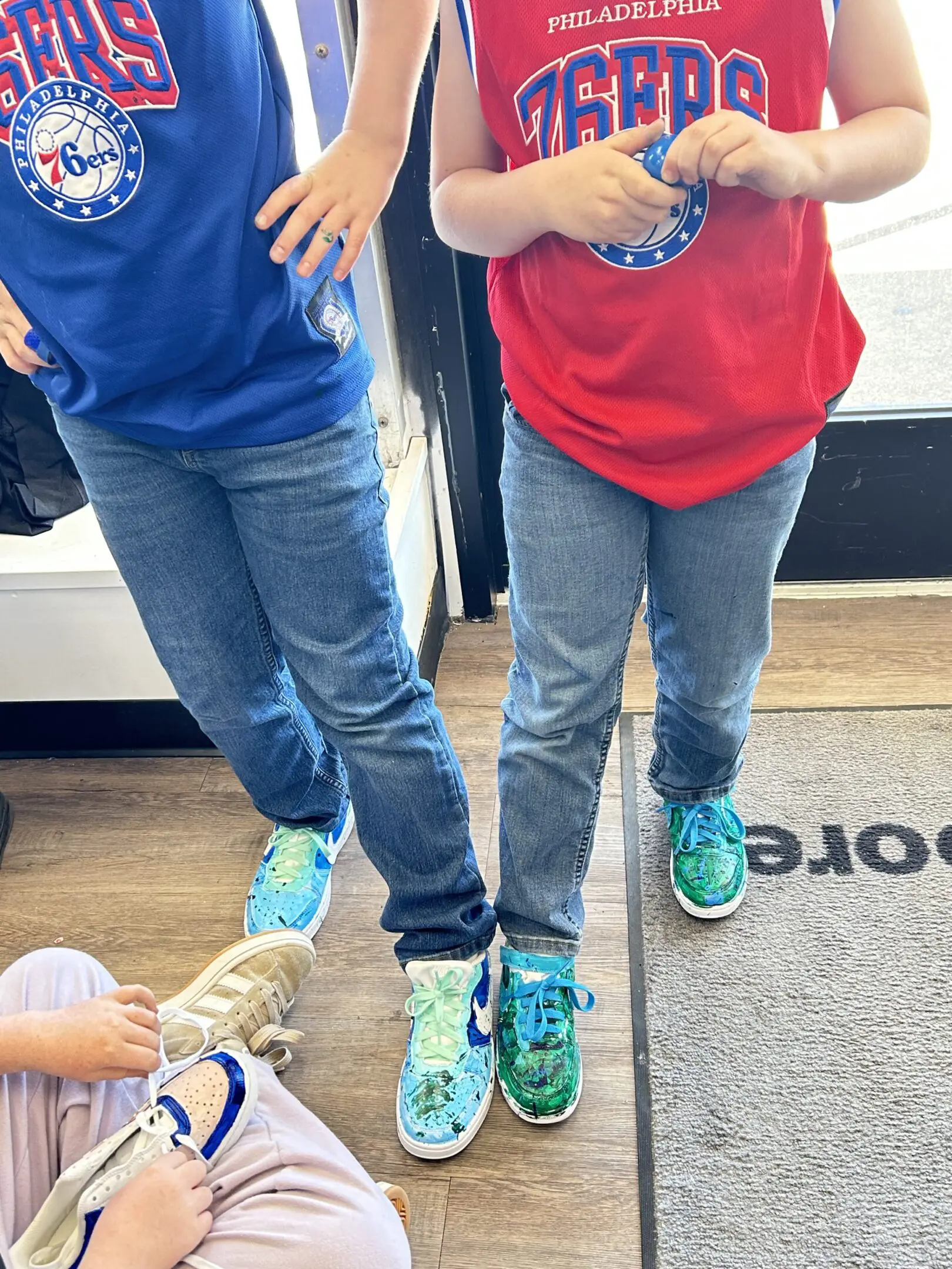 Two people standing side by side wearing colorful sneakers and jeans.